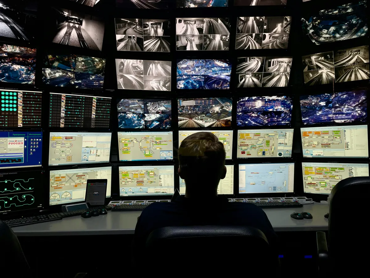 Operador frente a un muro de monitores en una sala de monitoreo
